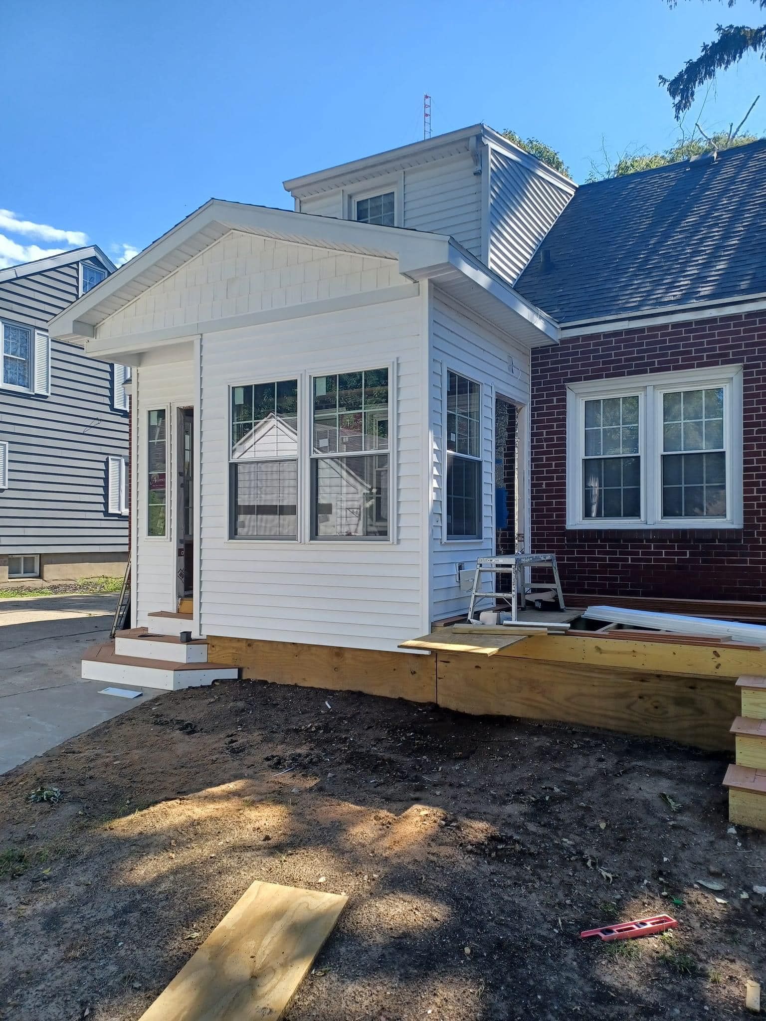 A small white house is being built next to a brick house.
