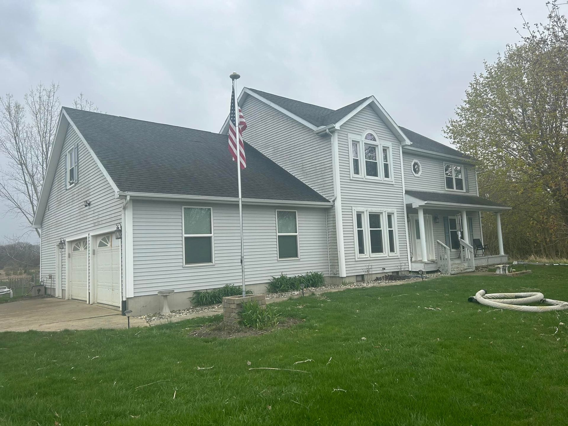 A large white house with a black roof and an american flag in front of it.