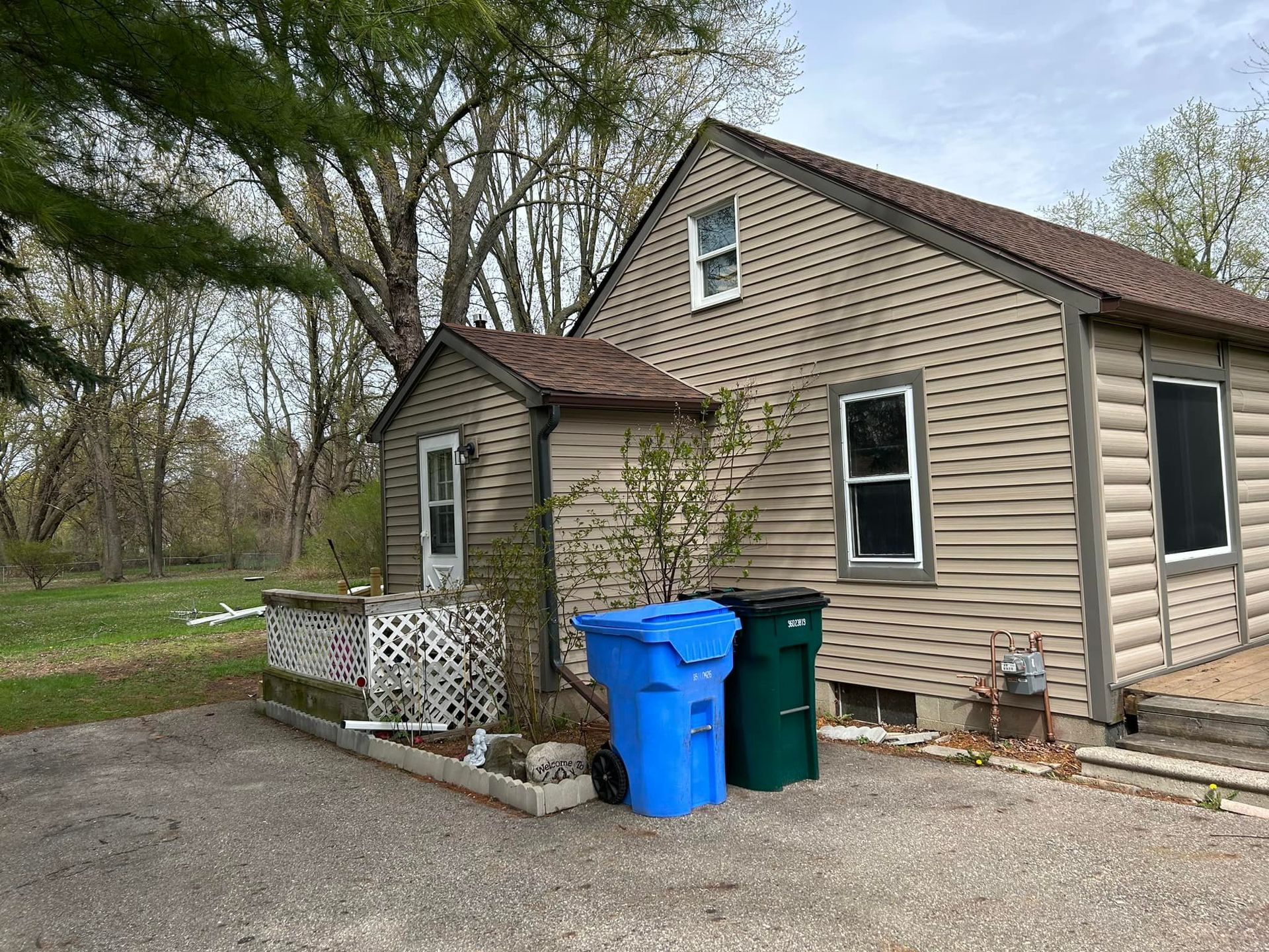 A small house with two trash cans in front of it.