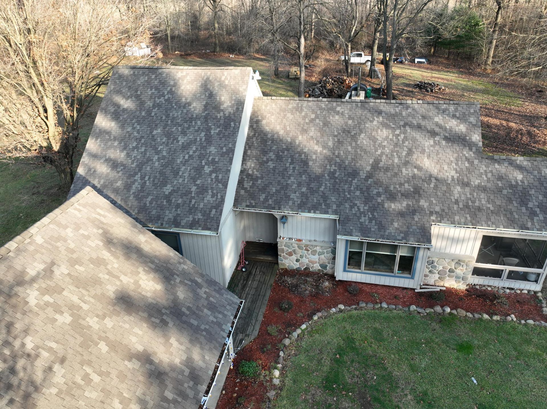 An aerial view of a house with a gray roof surrounded by trees.