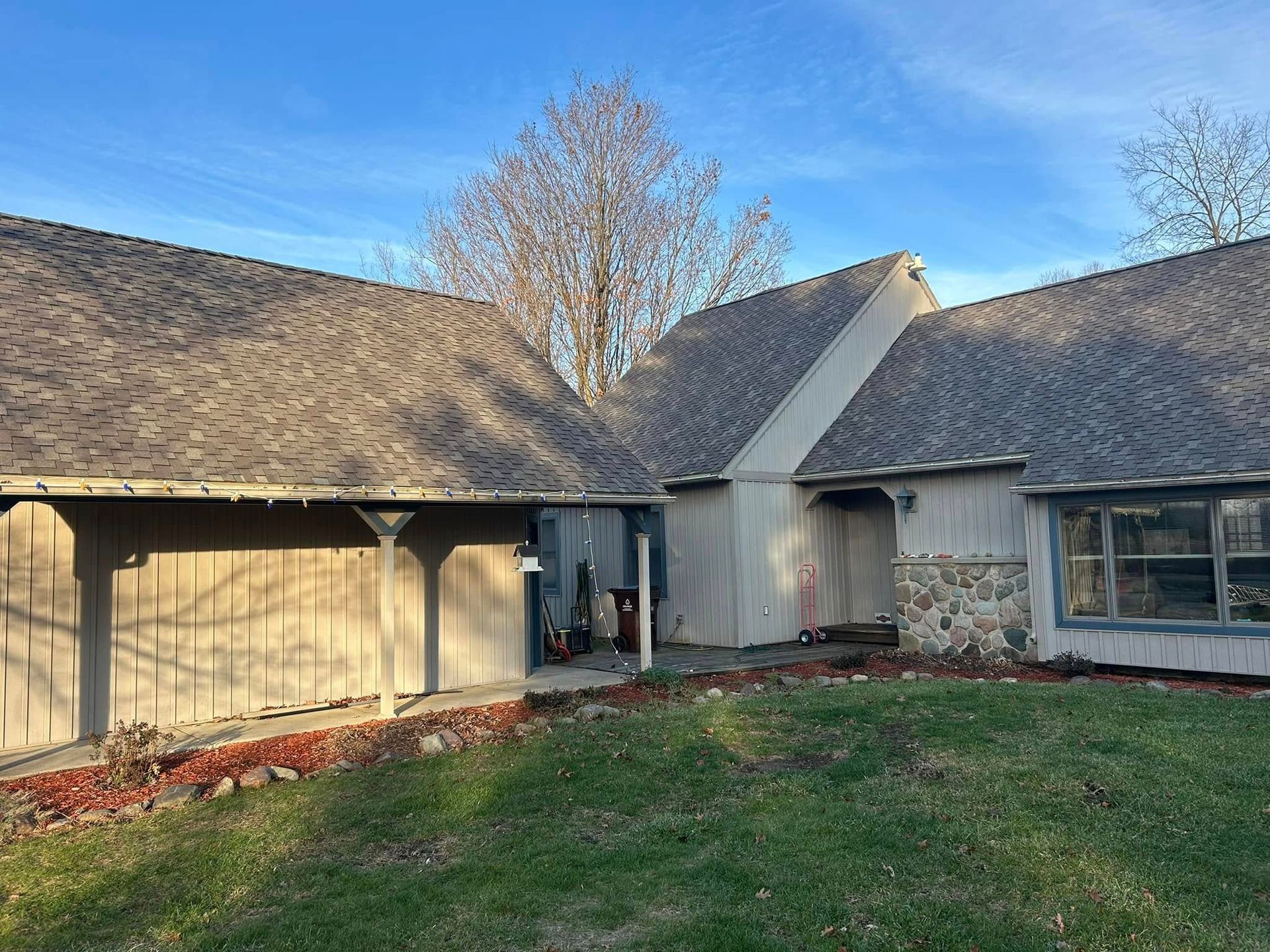 A large house with a gray roof is sitting on top of a lush green field.