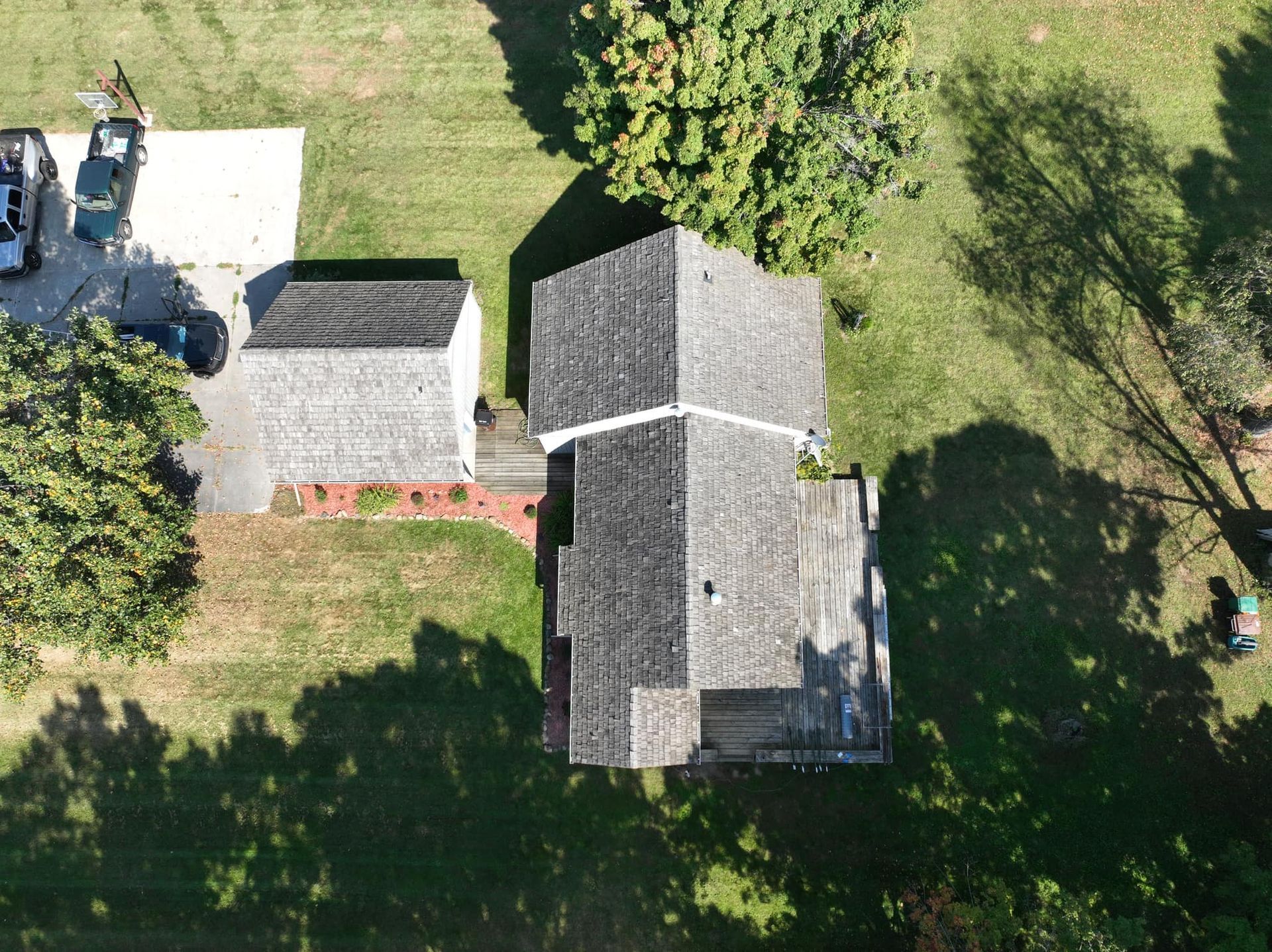An aerial view of a house and a garage surrounded by trees.