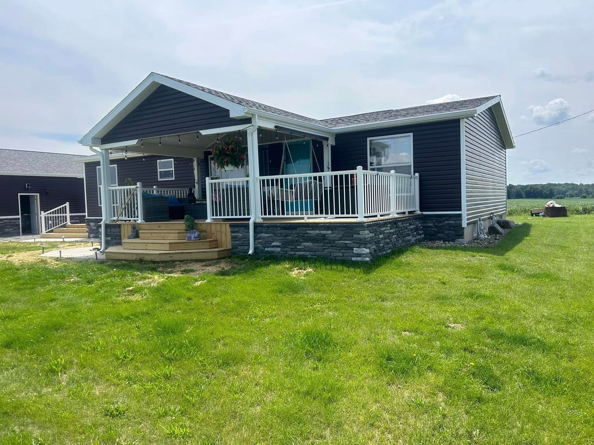 A small house with a porch in the middle of a grassy field.