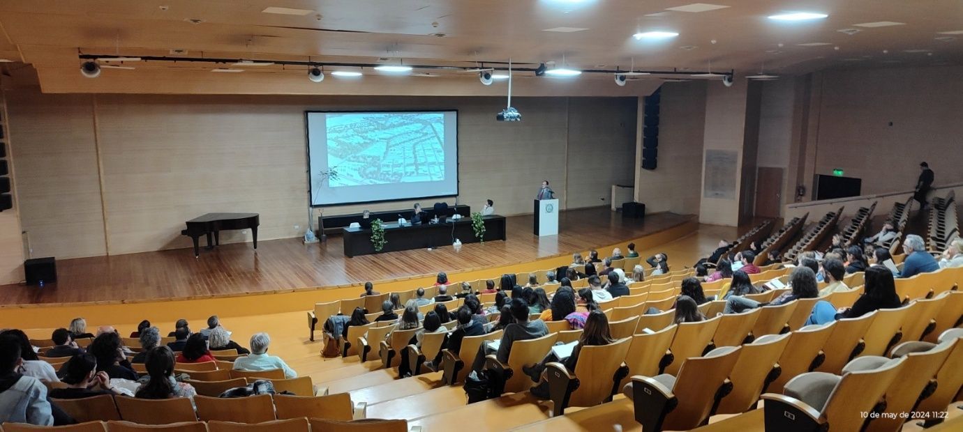 Un gran auditorio lleno de gente y una pantalla de proyección.