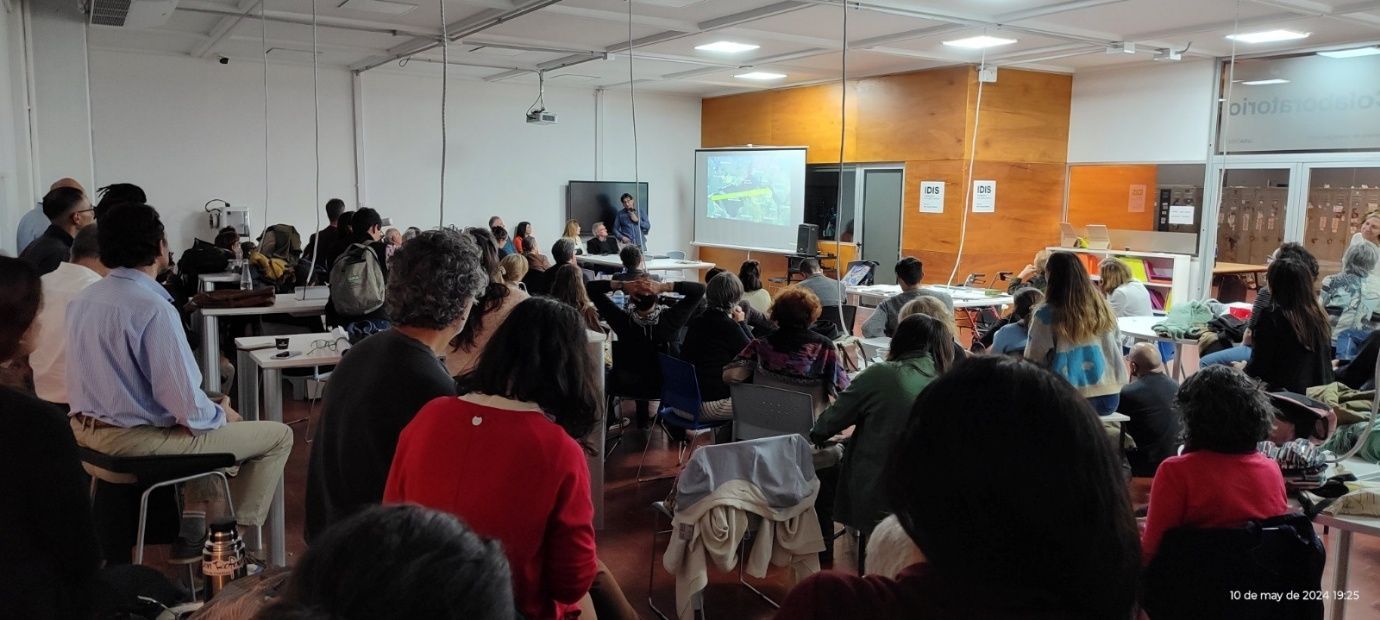 Un grupo grande de personas está sentado en una sala viendo una presentación.