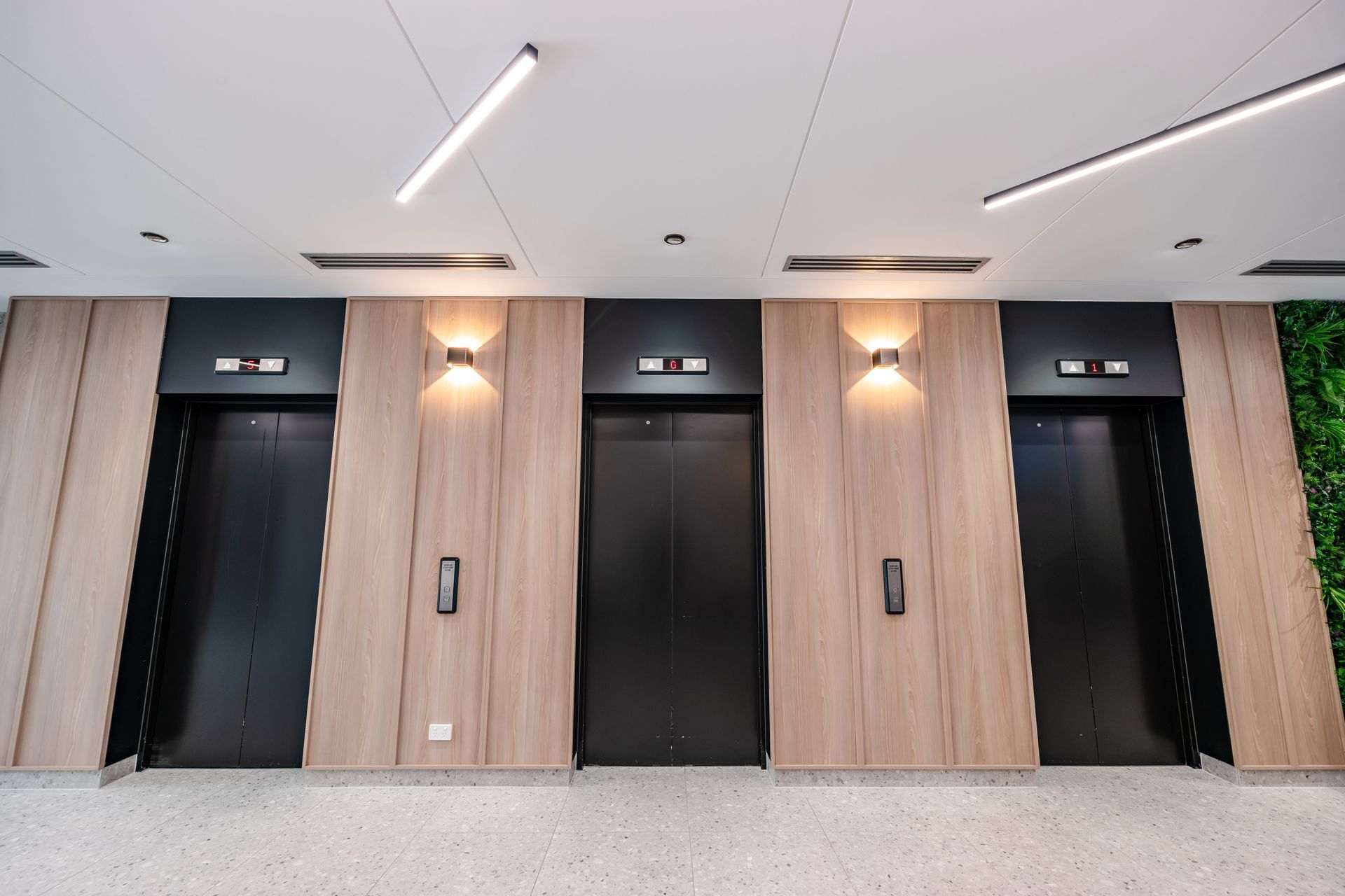 A Row Of Elevators In A Building With Wooden Walls And Black Doors – Brendale, QLD - DB Electrical