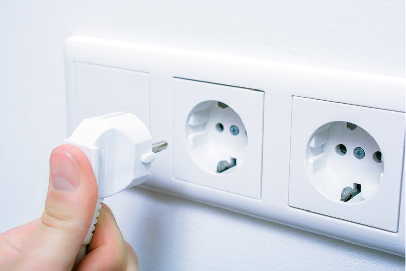 A Person Is Plugging A Plug Into A Wall Socket – Brendale, QLD - DB Electrical
