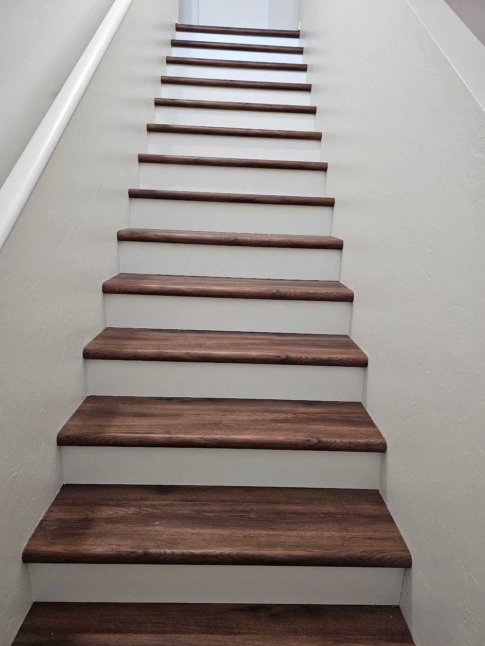 Wooden staircase with brown treads and white risers, ascending.
