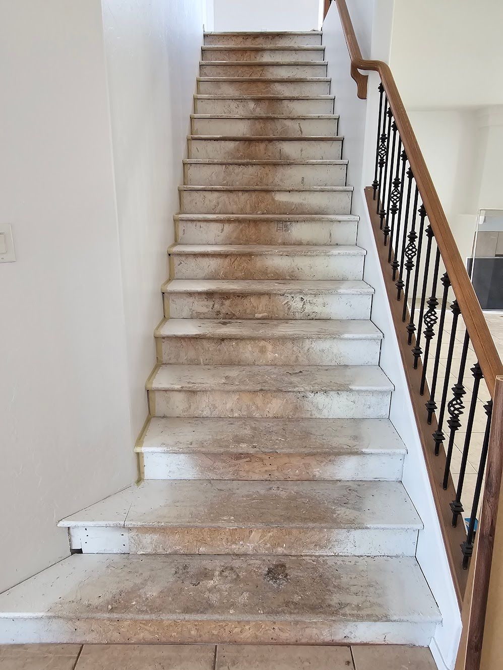Staircase with worn, dirty steps. A wooden handrail is on the right side.