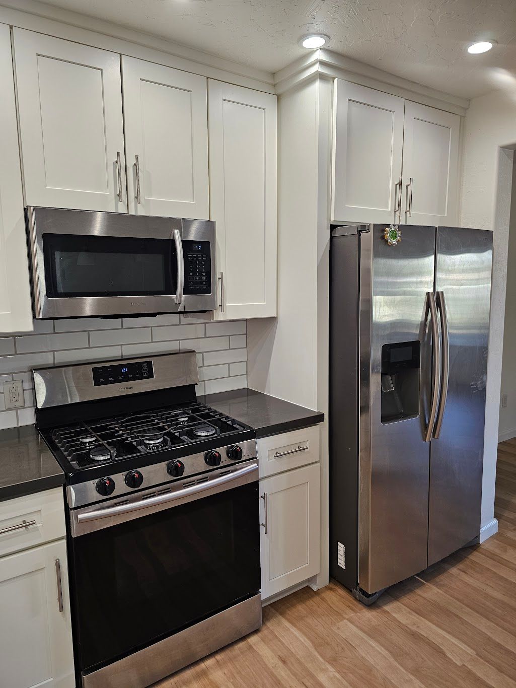 Kitchen with white cabinets, stainless steel appliances, and dark countertops.