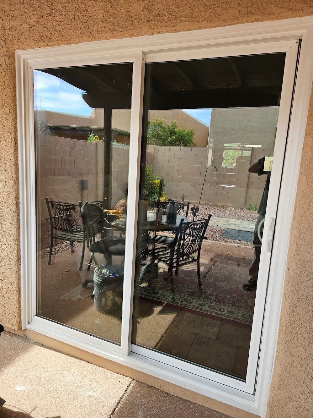 White-framed sliding glass door reflecting outdoor patio with table and chairs.