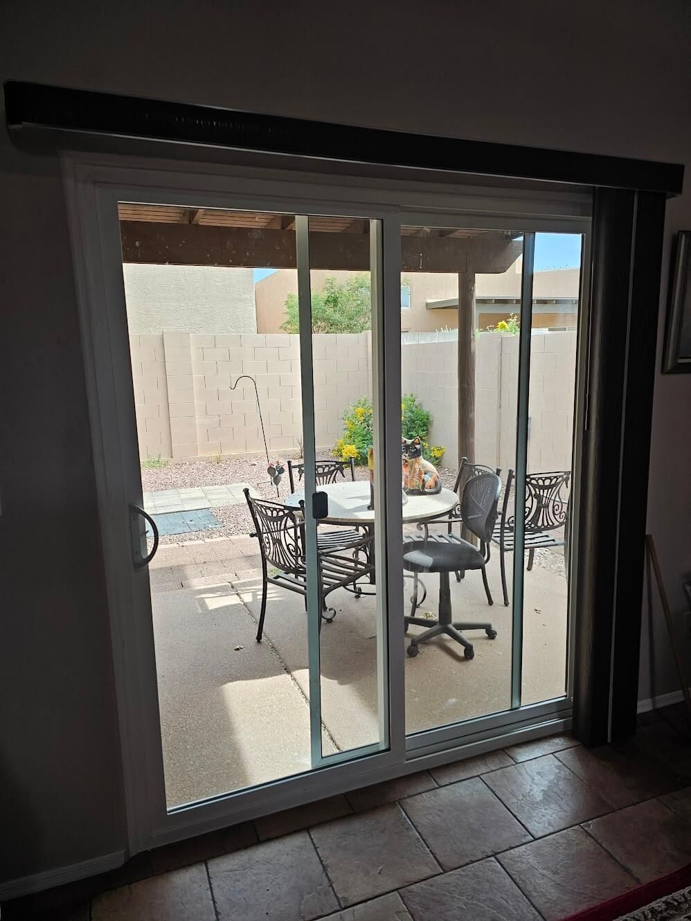 Sliding glass door open to a patio with table, chairs, and shade structure.