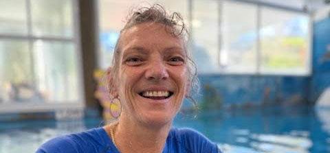 Woman Smiles Near a Swimming Pool. She Wears a Blue Shirt and Hoop Earrings — Swim Care Boambee in Coffs Harbour, NSW