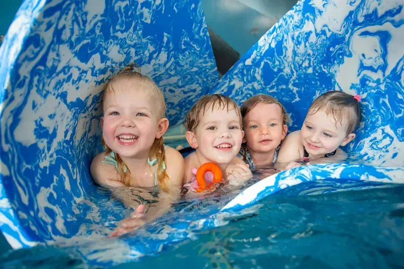 Four Young Children in A Pool, Lying on A Flotation Device — Swim Care Boambee in Boambee, NSW