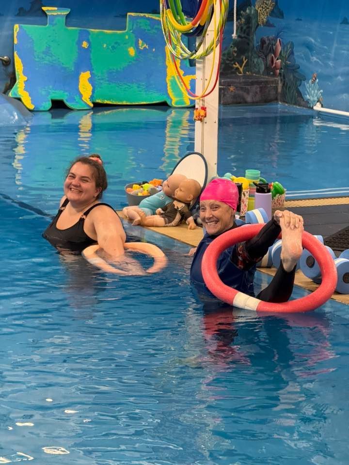 Two ladies are standing in a pool while one is wearing a neon pink swimming cap — Swim Care Boambee in Coffs Harbour, NSW