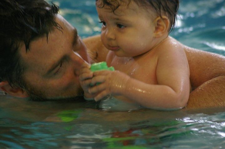 Man Holds a Baby in a Swimming Pool