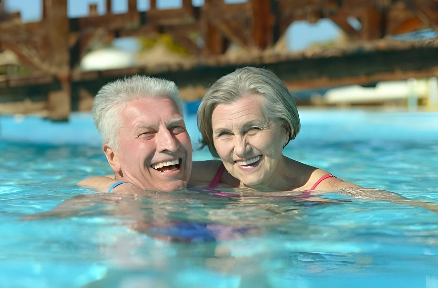 A Senior Couple Smiling While Swimming In A Clear Blue Pool