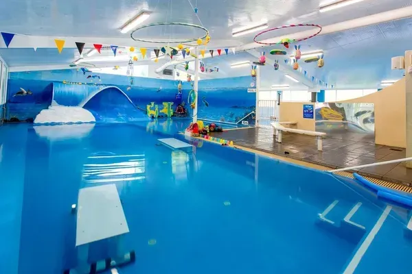Young Woman in Blue Shirt Smiles in a Swimming Pool — Swim Care Boambee in Coffs Harbour, NSW
