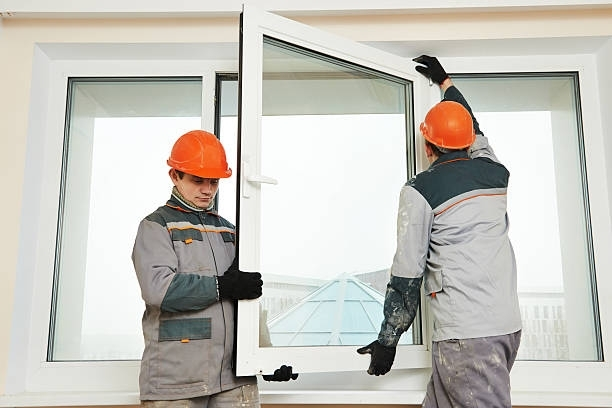 Residential window repair in progress with two workers in high-visibility vests.