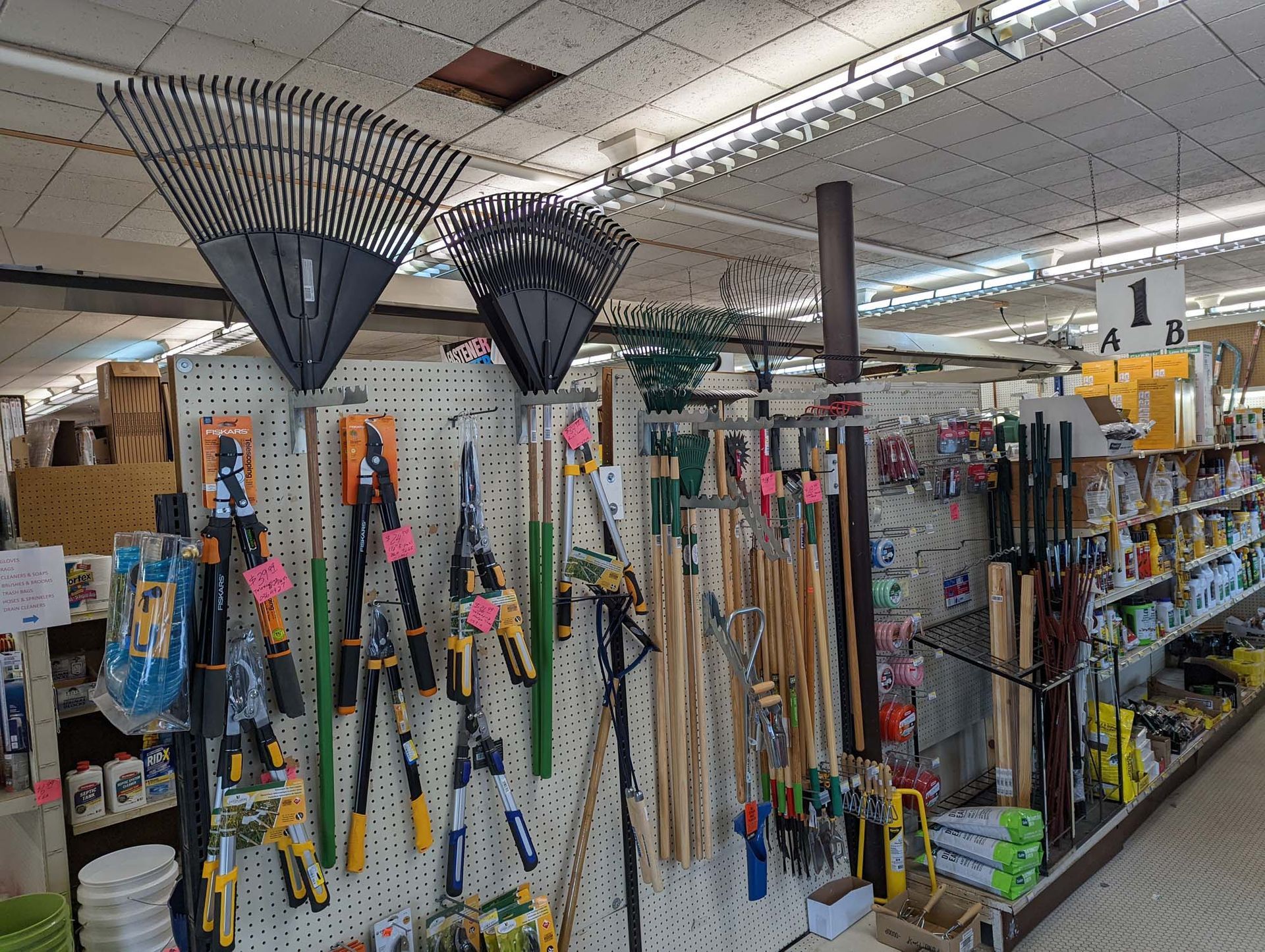 A bunch of gardening tools are hanging on a wall in a store.