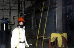 a man in a hard hat and gas mask is standing in a dark room .