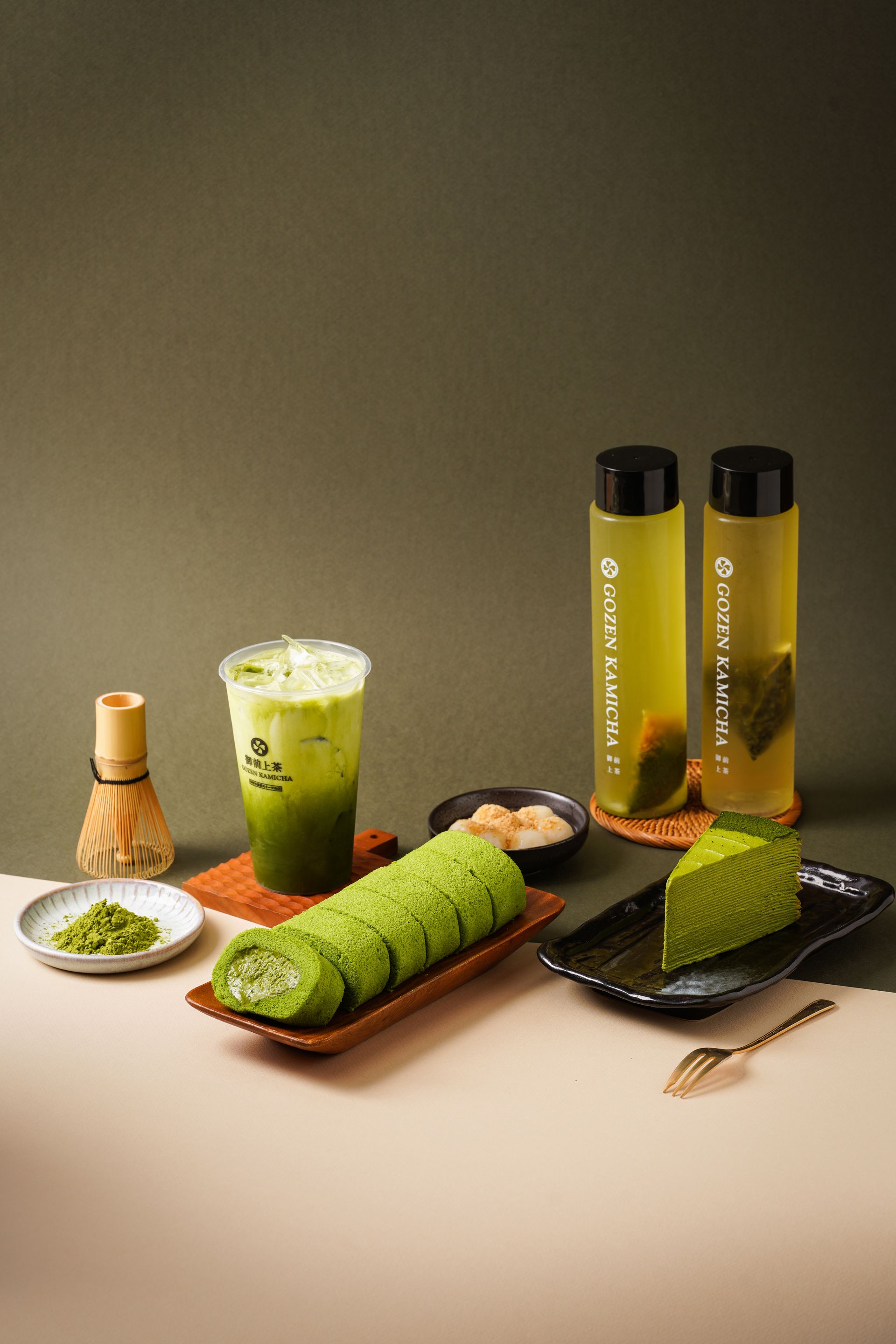 Green tea desserts and drinks arranged on a table, including matcha cake rolls, a parfait, and bottled beverages