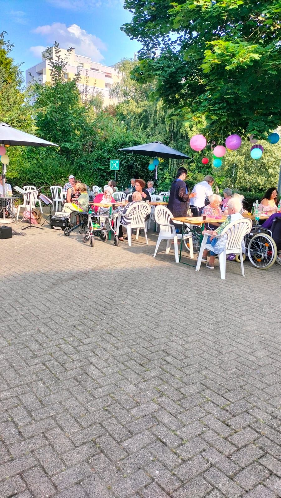 Eine Gruppe von Leuten sitzt an Tischen in einem Park.