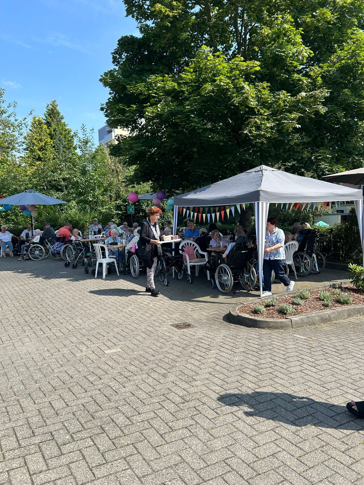 Eine Gruppe von Menschen im Rollstuhl sitzt unter einem weißen Zelt.