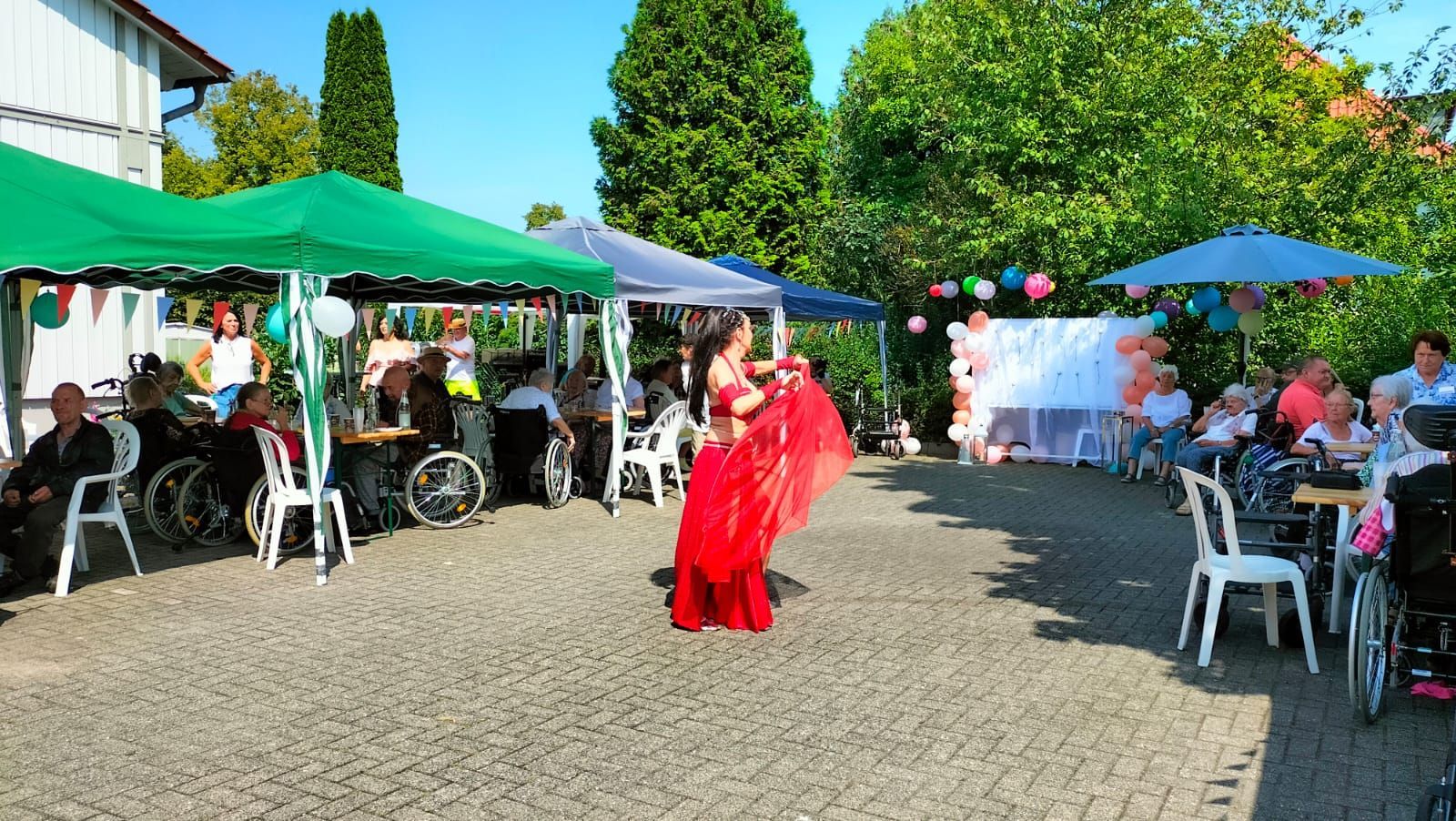 Eine Frau in einem roten Kleid tanzt vor einer Menschenmenge.