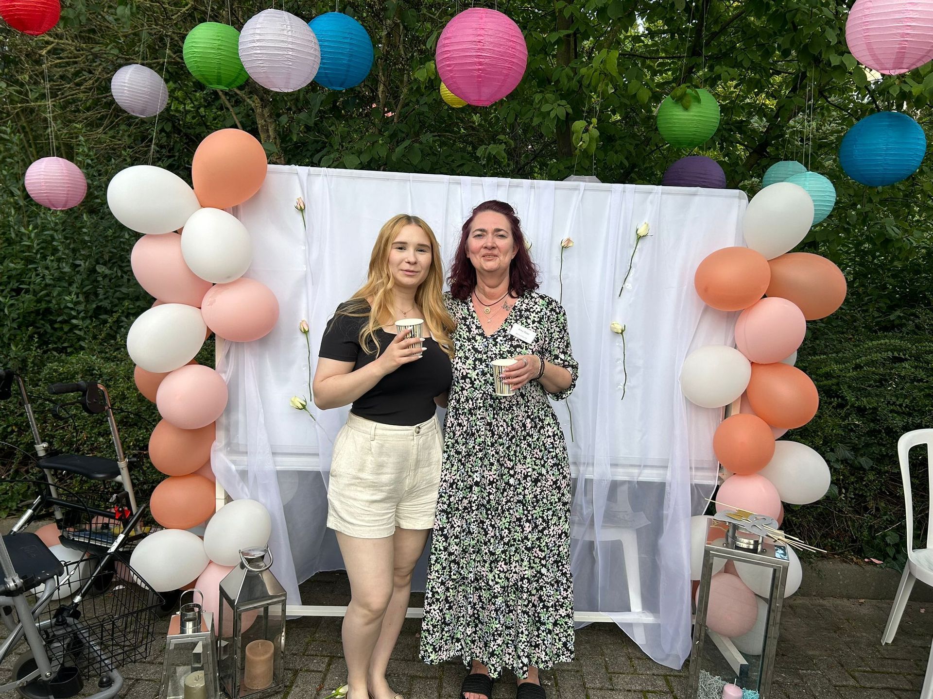 Zwei Frauen stehen nebeneinander vor Luftballons und Laternen.