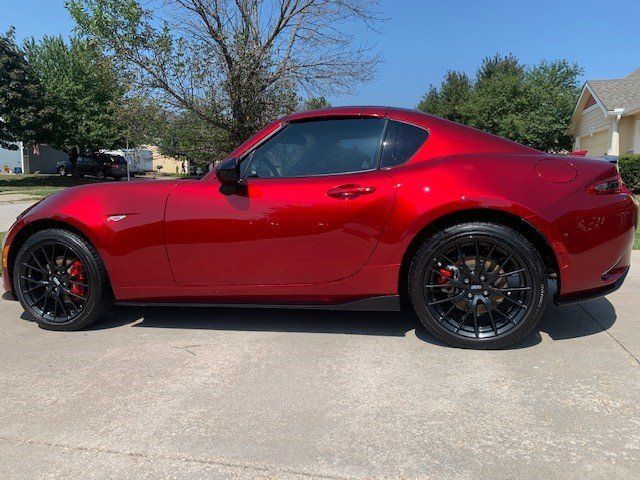 A red sports car is parked in a driveway in front of a house.
