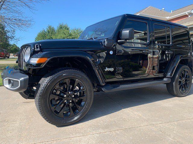 A black jeep wrangler is parked in a driveway.