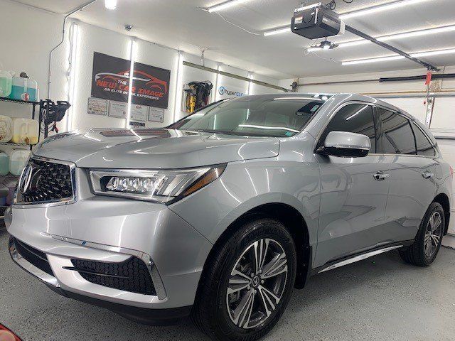 A silver suv is parked in a garage under a garage door.