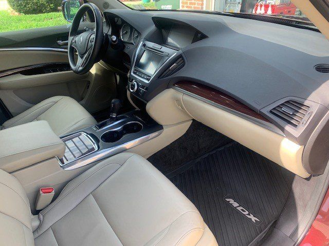 The interior of a red acura mdx is shown