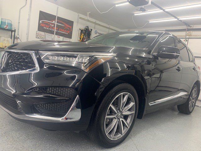 A black car is parked in a garage next to a garage door.