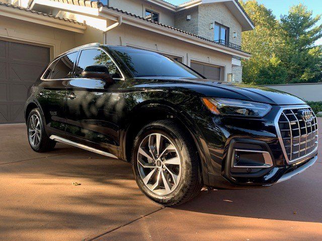 A black audi q5 is parked in a driveway in front of a house.