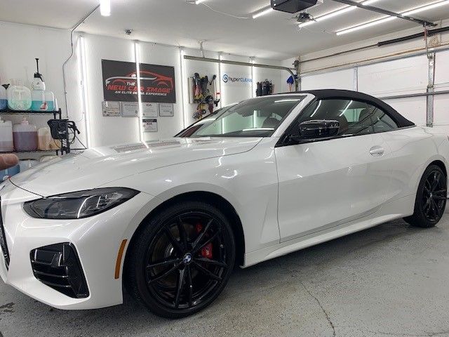 A white convertible bmw is parked in a garage.