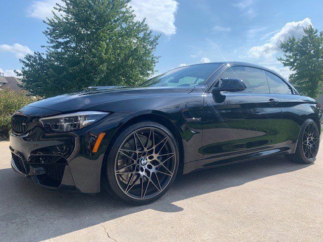 A black bmw m4 convertible is parked in a driveway.