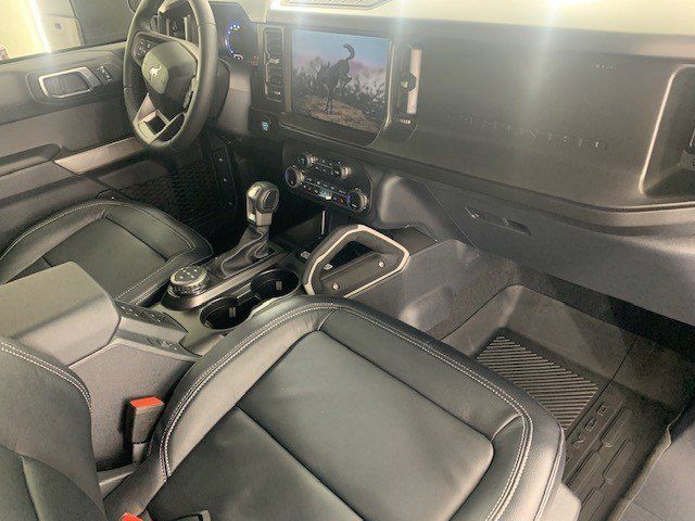 The interior of a ford bronco with black leather seats and a steering wheel.