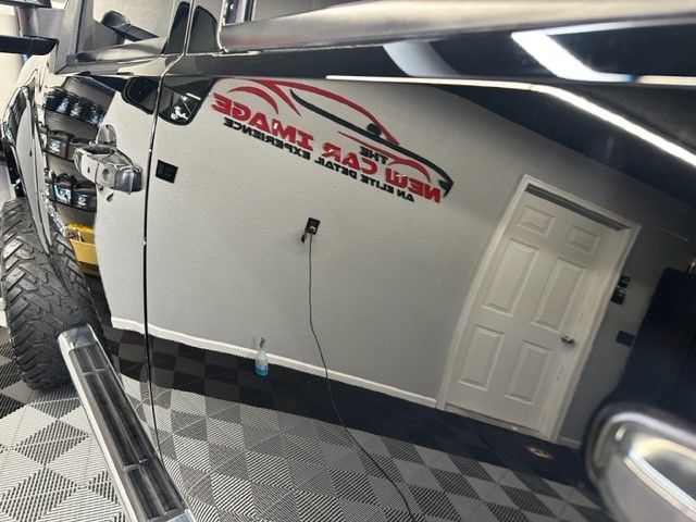 A black truck is parked in a garage with a adams rad wax sticker on the side