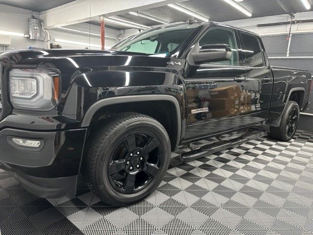 A black truck is parked on a checkered floor in a garage.