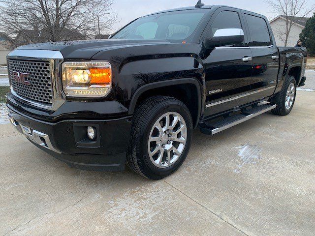 A black gmc sierra pickup truck is parked on the side of the road.