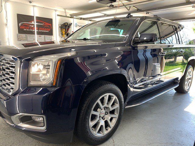 A blue gmc yukon is parked in a garage.