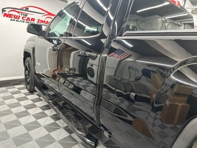 A black truck is parked in a garage with the new car image logo on the wall