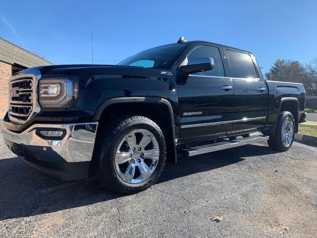 A black gmc sierra pickup truck is parked on the side of the road.