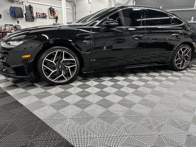 A black car is parked in a garage on a checkered floor.