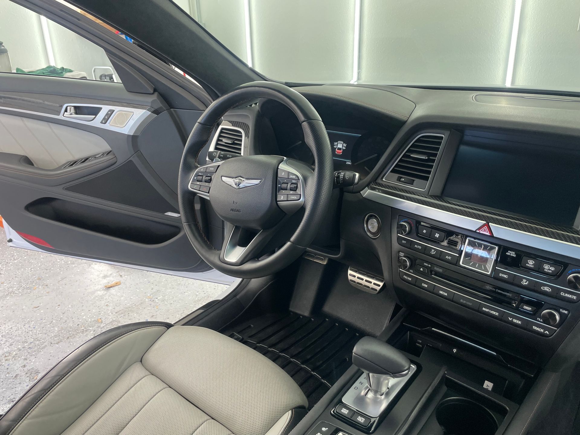 The interior of a car with the door open and the steering wheel visible.