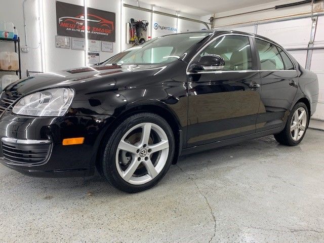 A black volkswagen jetta is parked in a garage.