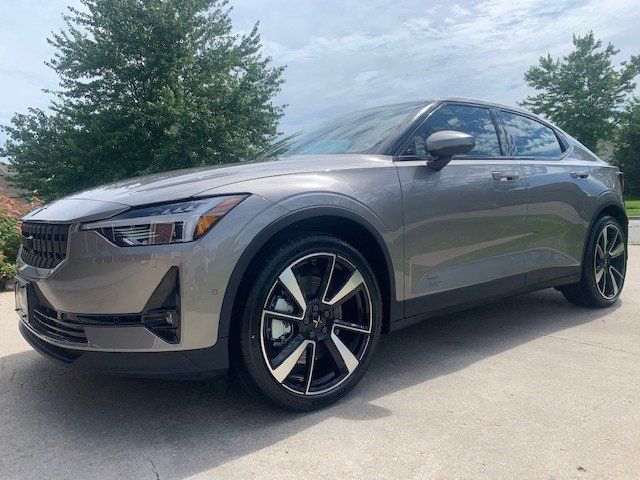 A gray volvo polestar 2 is parked in a driveway.
