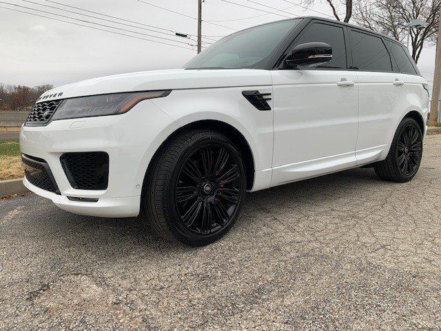 A white range rover sport is parked on the side of the road.